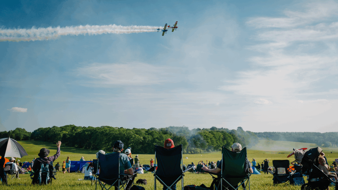 People watchign a plane fly in a field