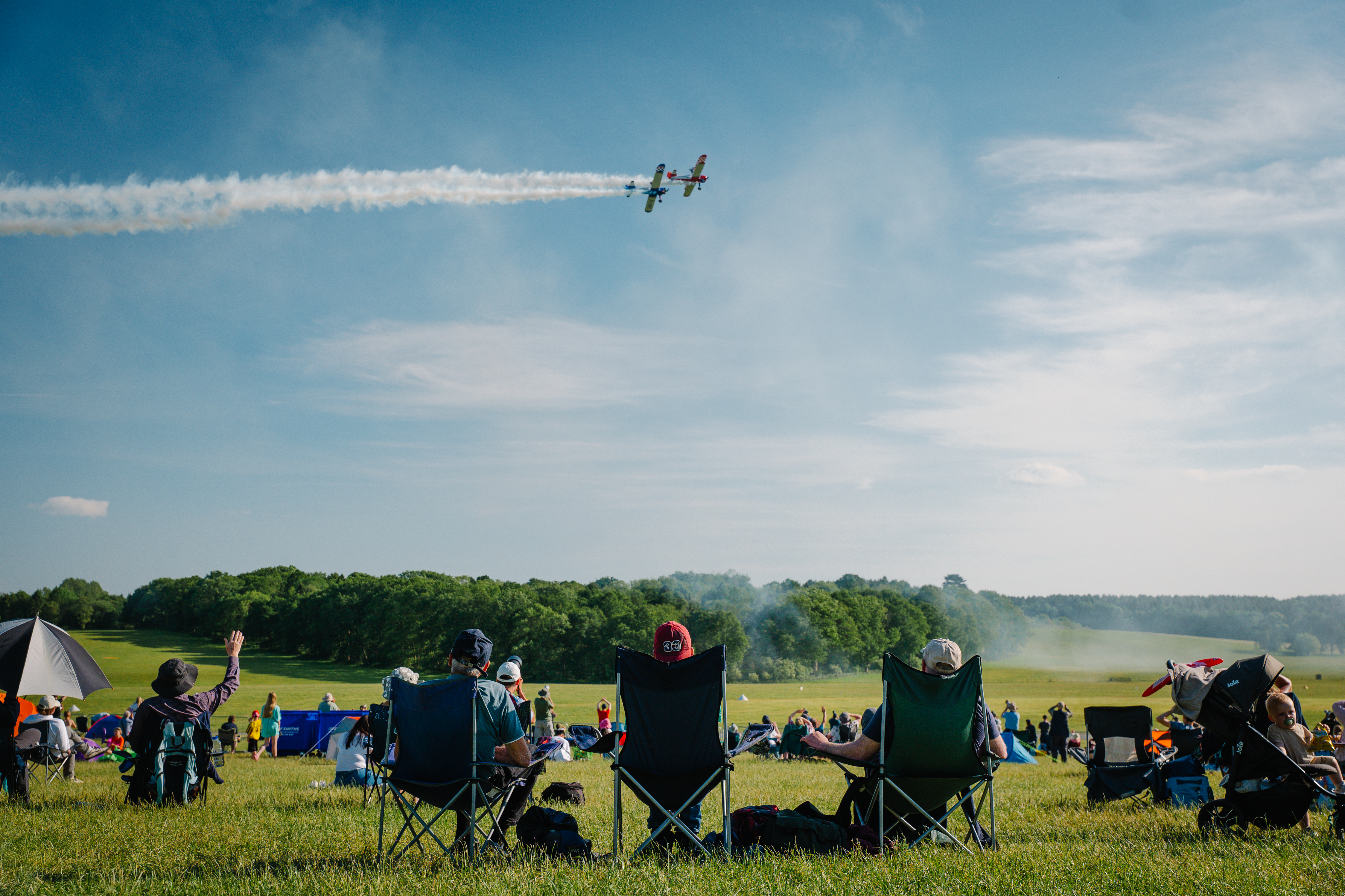 People watchign a plane fly in a field