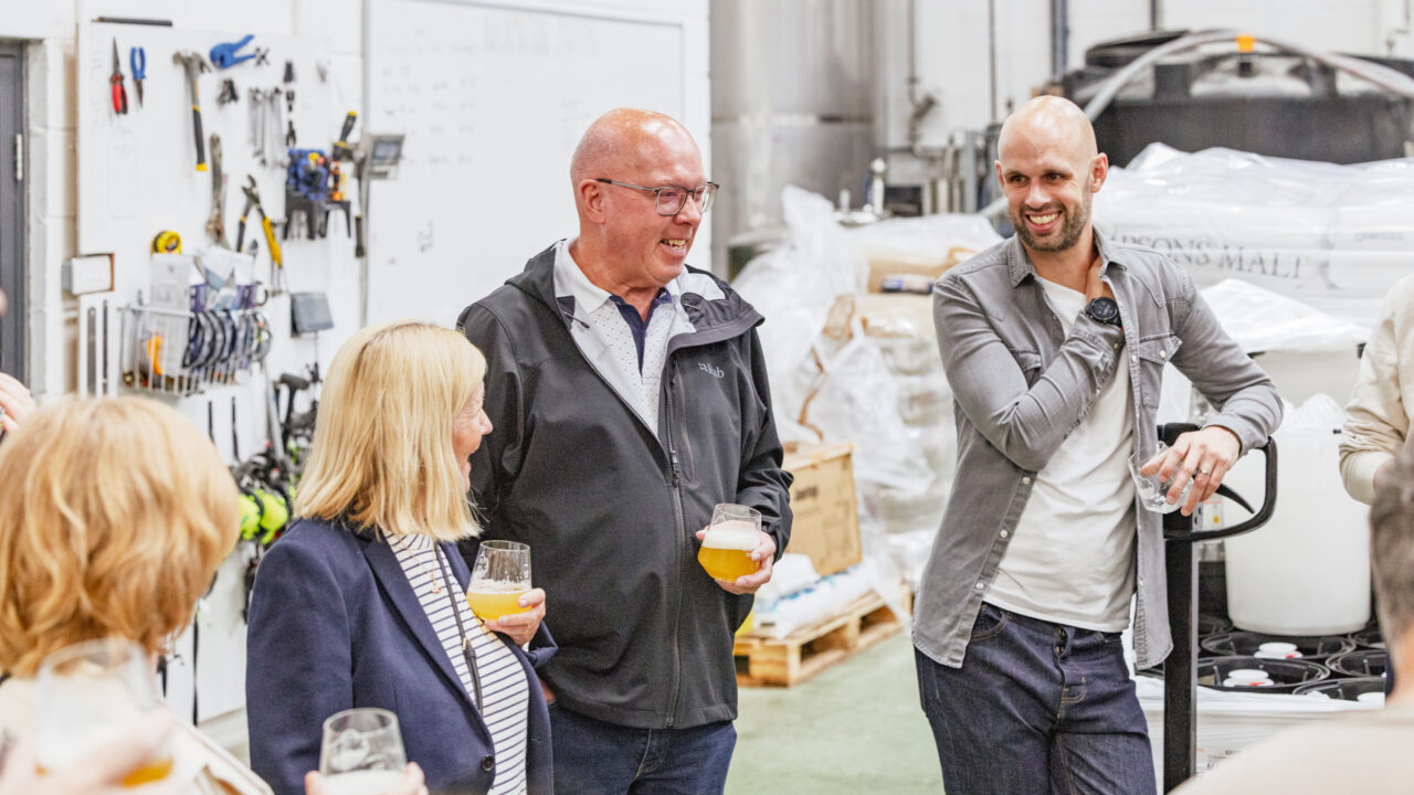 People in a warehouse smiling at a beer tating