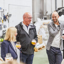 People in a warehouse smiling at a beer tating