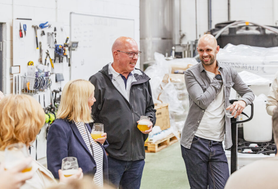 People in a warehouse smiling at a beer tating